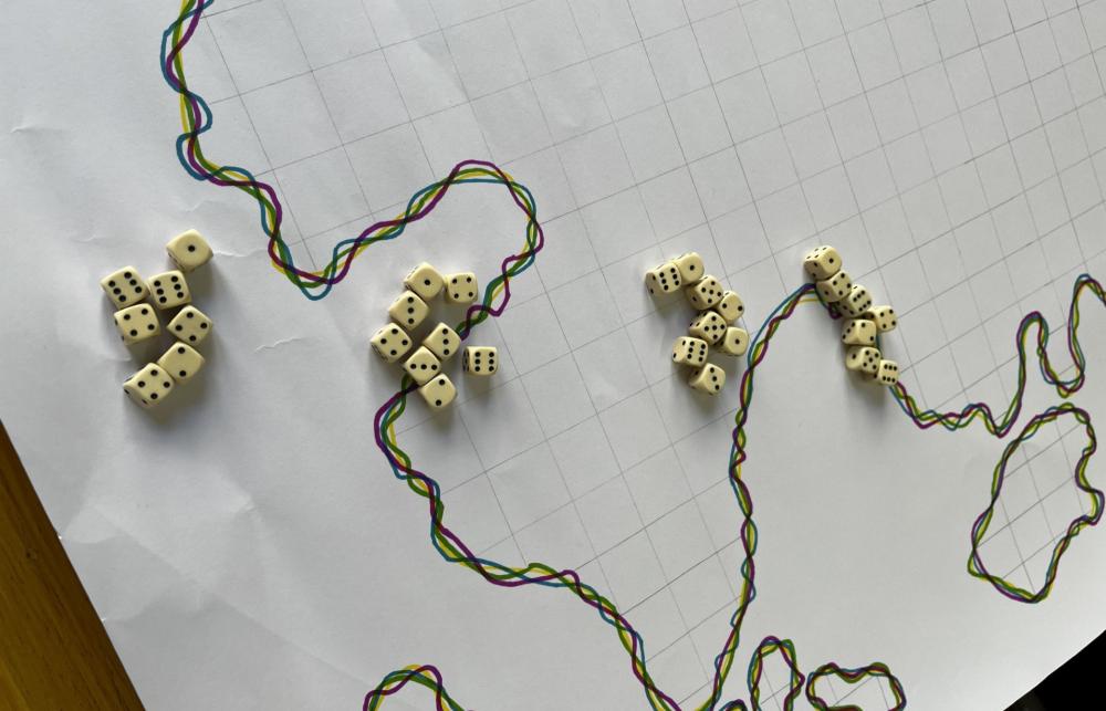Image shows the outline of a map drawn on paper in coloured pen. A handful of dice are sitting on the map.